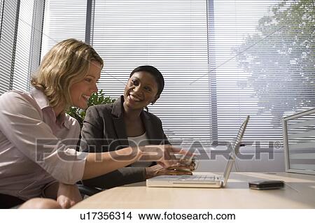Businesswomen using laptop together View Large Photo Image Picture - Businesswomen using laptop together. Fotosearch