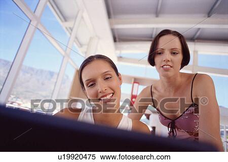 Stock Photography - Businesswomen using laptop together. Fotosearch