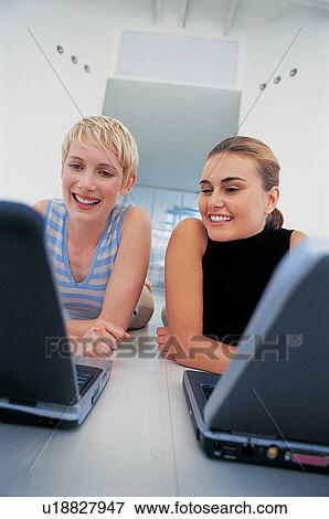Stock Photo - Businesswomen using laptops on floor. Fotosearch