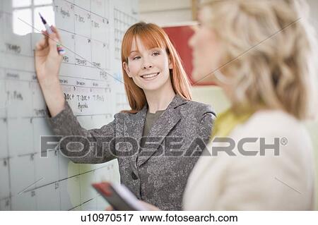 Stock Photo - Businesswomen writing on calendar. Fotosearch