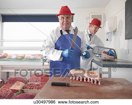 Stock Photograph - Butcher carving meat in shop. Fotosearch
