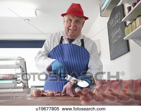 Stock Photography - Butcher carving meat in shop. Fotosearch