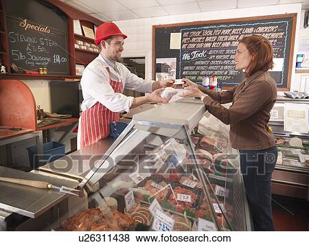 Butcher handing meat to customer View Large Photo Image Stock Photo - Butcher handing meat to customer. Fotosearch