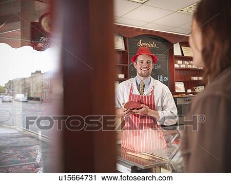 Butcher showing meat to customer View Large Photo Image Stock Image - Butcher showing meat to customer. Fotosearch