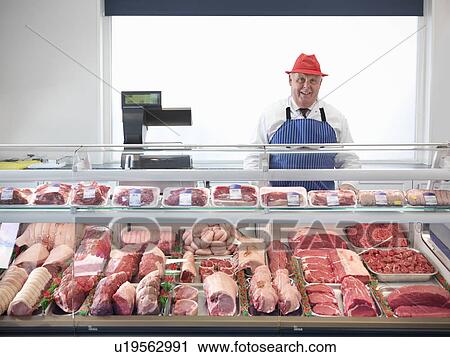 Butcher standing behind meat counter View Large Photo Image Stock Image - Butcher standing behind meat counter. Fotosearch