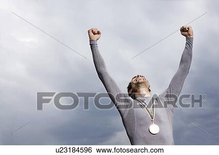 Stock Photograph - Cheering runner wearing medal. Fotosearch