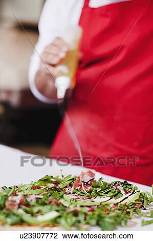 Chef drizzling oil over pizza View Large Photo Image Stock Image - Chef drizzling oil over pizza. Fotosearch