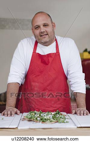 Stock Image - Chef with pizza in kitchen. Fotosearch