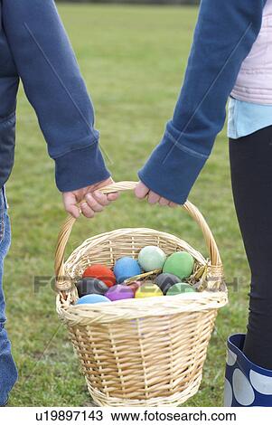 Stock Image - Children carrying basket of Easter eggs. Fotosearch