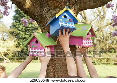 Stock Photo - Children hanging birdhouses in tree. Fotosearch