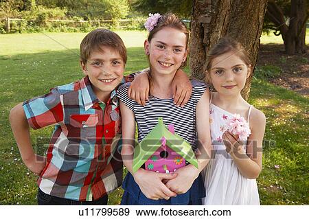 Children holding birdhouse in backyard View Large Photo Image Stock Photo - Children holding birdhouse in backyard. Fotosearch
