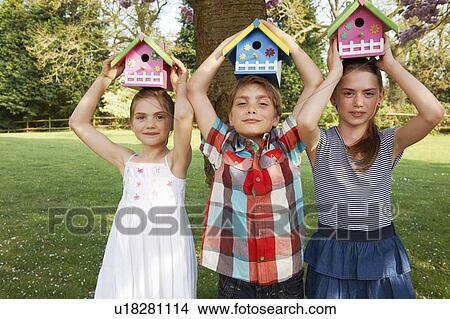 Picture - Children holding birdhouses in backyard. Fotosearch