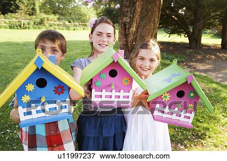 Children holding birdhouses in backyard View Large Photo Image Stock Photo - Children holding birdhouses in backyard. Fotosearch
