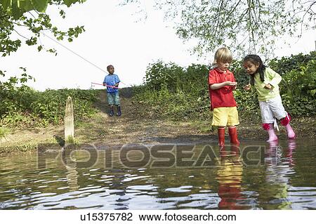 Children in rainboots playing in pond View Large Photo Image Stock Image - Children in rainboots playing in pond. Fotosearch