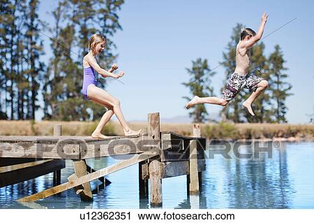 Stock Image - Children jumping into lake from jetty. Fotosearch