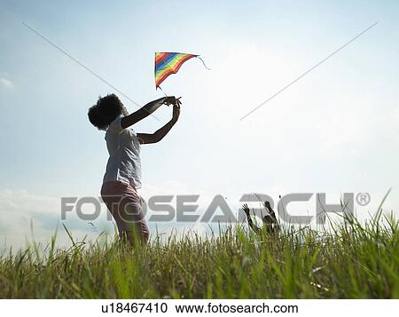 Stock Image - Children playing with kite in field. Fotosearch