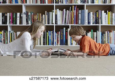 Stock Image - Children reading by bookshelves. Fotosearch