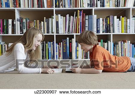 Stock Photo - Children reading by bookshelves. Fotosearch