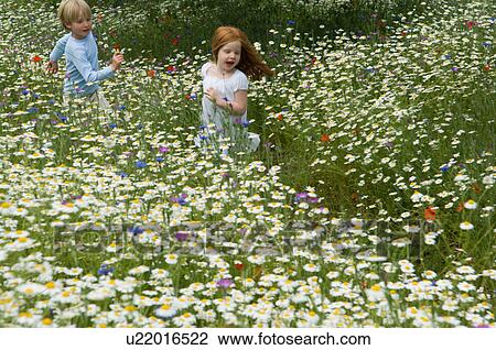 Stock Image - Children running in field of flowers. Fotosearch