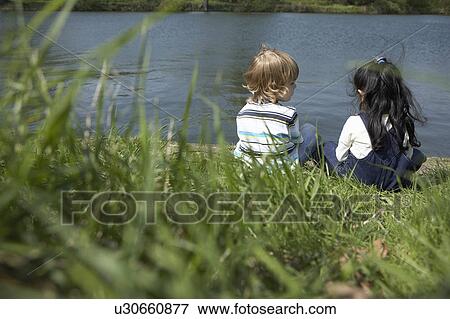 Stock Photo - Children sitting on riverbank together. Fotosearch