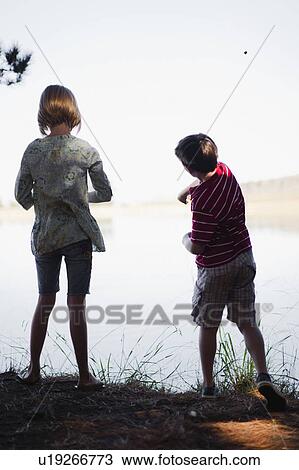 Stock Image - Children skipping stones in lake. Fotosearch