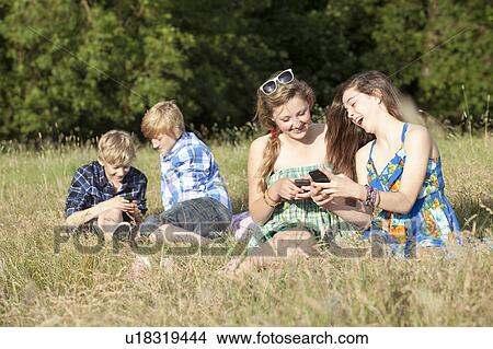 Picture - Children using cell phones in field. Fotosearch