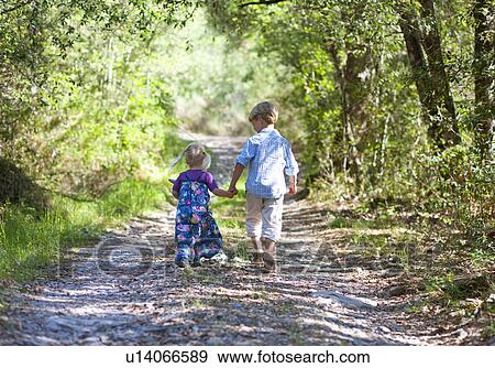 Stock Photo - Children walking hand-in-hand outdoors. Fotosearch