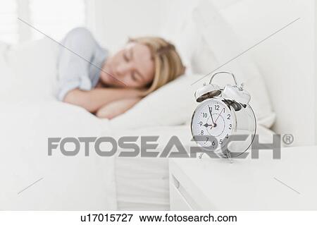 Stock Photo - Close up of alarm clock on bedside table. Fotosearch