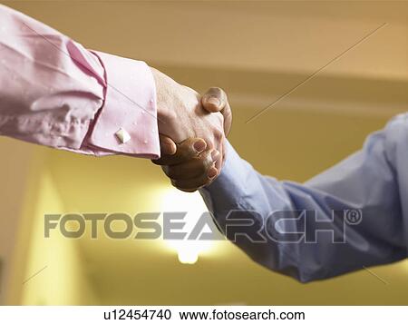 Stock Image - Close up of businessmen shaking hands. Fotosearch