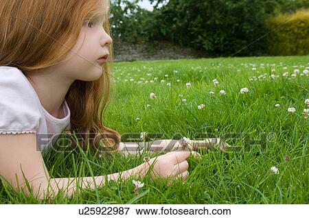 Close up of girl laying in grass View Large Photo Image Stock Photo - Close up of girl laying in grass. Fotosearch