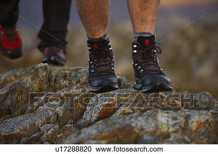 Stock Image - Close up of hiking boots on mountainside. Fotosearch