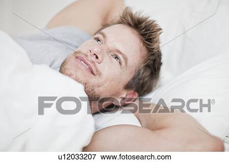 Close up of man relaxing in bed View Large Photo Image Stock Photo - Close up of man relaxing in bed. Fotosearch