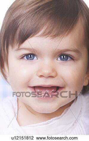 Stock Image - Close up of smiling baby girl’s face. Fotosearch