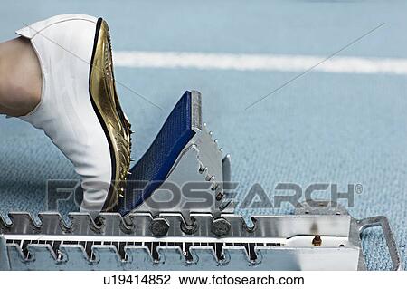 Stock Image - Close up of spiked shoe at start block. Fotosearch