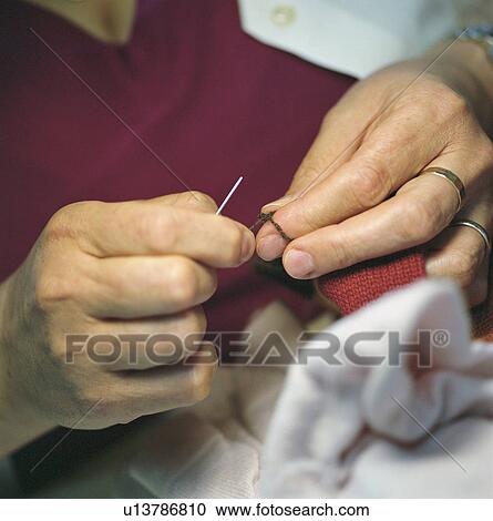 Stock Image - Close up of woman sewing. Fotosearch