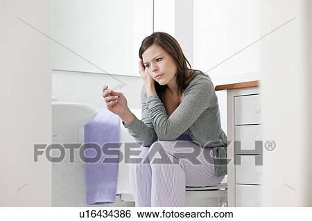 Stock Photograph - Concerned woman taking pregnancy test. Fotosearch