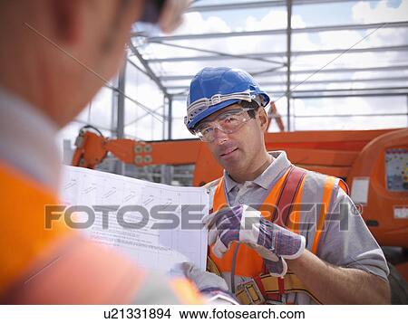 Picture - Construction workers reading blueprints. Fotosearch
