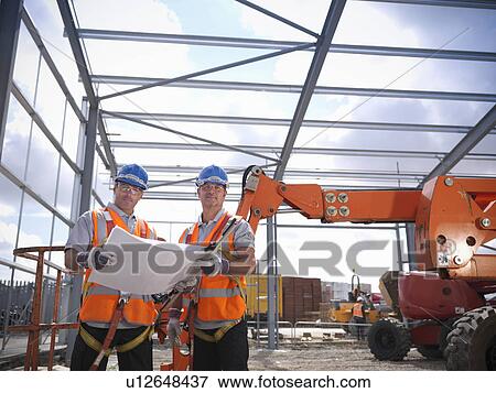 Stock Photo - Construction workers reading blueprints. Fotosearch