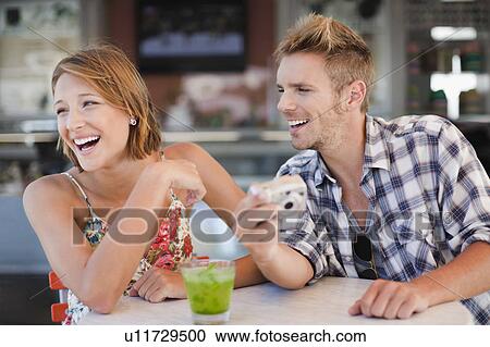 Stock Image - Couple admiring photos at cafe. Fotosearch