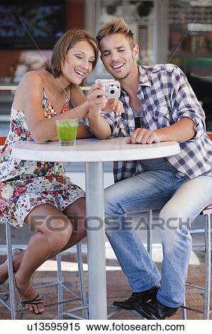 Couple admiring photos at cafe View Large Photo Image Stock Photography - Couple admiring photos at cafe. Fotosearch