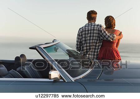 Stock Photography - Couple admiring view on convertible. Fotosearch