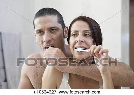 Couple brushing their teeth in bathroom View Large Photo Image Stock Photo - Couple brushing their teeth in bathroom. Fotosearch