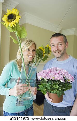 Couple carrying flowers in new home View Large Photo Image Stock Image - Couple carrying flowers in new home. Fotosearch