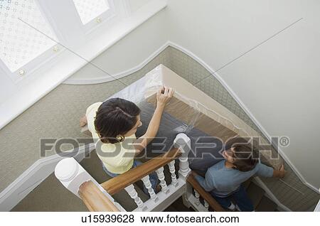 Stock Photo - Couple carrying mattress upstairs. Fotosearch