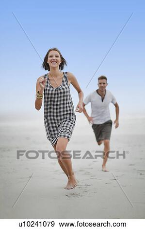 Couple chasing each other on beach View Large Photo Image Stock Photo - Couple chasing each other on beach. Fotosearch