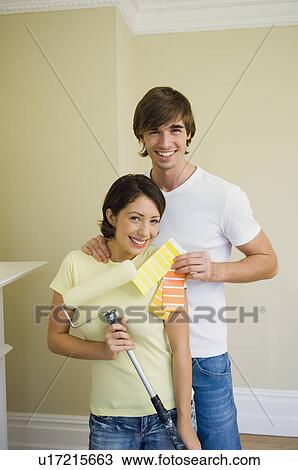 Stock Image - Couple choosing paint color in new home. Fotosearch