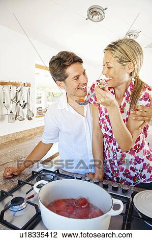 Stock Image - Couple cooking together in kitchen. Fotosearch