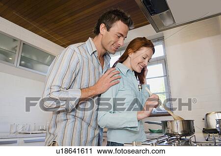 Stock Image - Couple cooking together in kitchen. Fotosearch