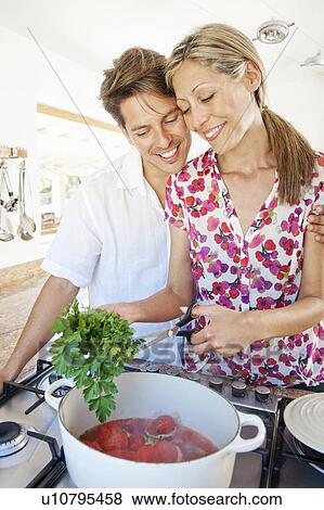 Couple cooking together in kitchen View Large Photo Image Stock Photo - Couple cooking together in kitchen. Fotosearch
