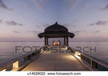 Stock Image - Couple eating on tropical dock. Fotosearch